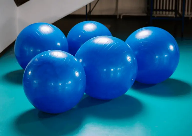 A collection of 5 large blue treibballs grouped together on an aqua colored floor